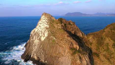 Cinematic-revealing-drone-shot-of-large-stone-in-ocean-at-Kyushu-Japan