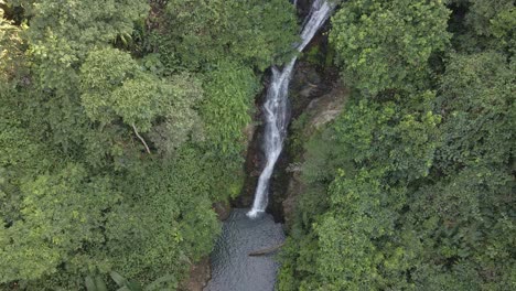 Aerial-descending-wide-shot-of-a-beautiful-waterfall-hidden-in-the-tropical-rainforest-jungle-in-South-East-Asia