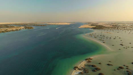 Drone-aerial-pan-across-turquoise-ocean-rivers-split-by-sand-bank-with-mangroves