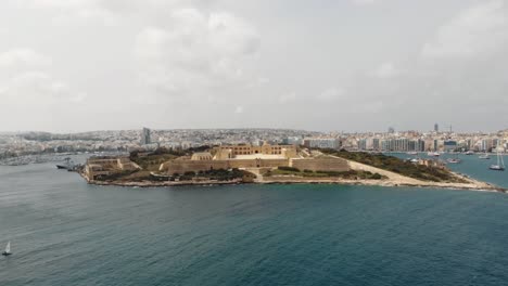 Panoramic-view-of-Manoel-Island-surrounded-by-Sliema-city-seascape-in-Malta---Slow-orbit-aerial-shot