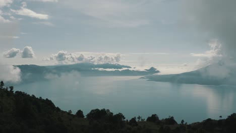 Drone-aerial-view,-flying-high-over-the-trees-revealing-blue-lake-Atitlan,-Guatemala