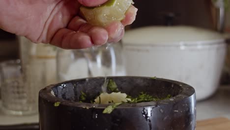 Squeezing-lemon-juice-into-a-black-ceramic-bowl-with-herbs-and-spices