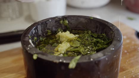 Adding-olive-oil-into-a-bowl-with-garlic-and-herbs