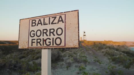 Revealing-Shot-Of-Phrygian-Cap-Beacon-Behind-Baliza-Gorro-Frigio-Signage-In-Puerto-Madryn,-Chubut,-Argentina---slow-motion