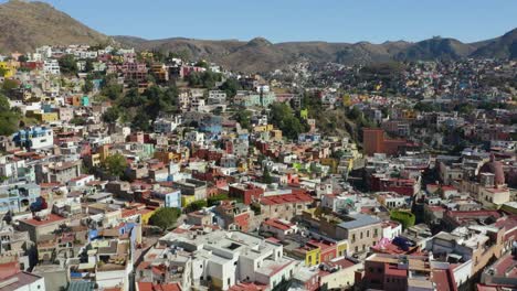 Drone-Elevates-to-Reveal-Colorful-Latin-American-City-Built-into-Mountains,-Mexico