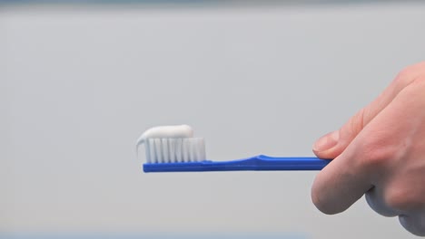 Eine-Frau-Im-Badezimmer-Drückt-Weiße-Zahnpasta-Aus-Einer-Tube-Auf-Eine-Blaue-Zahnbürste-Auf-Weißem-Hintergrund,-Putzt-Sich-Die-Zähne,-Morgens-Und-Abends,-Hygiene