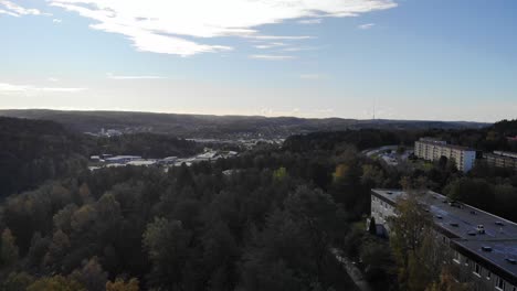 Drone-lift-off-above-trees-to-reveal-cityscape-of-Gothenburg,-Sweden