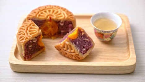 Chinese-moon-cake-purple-sweet-potato-and-egg-yolk-flavour-with-tea-on-wood-plate