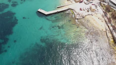 Bird's-eye-view-of-Pier-extending-over-Clear-Mediterranean-water-on-the-shores-of-Sliema,-in-Malta---Fly-over-aerial-shot