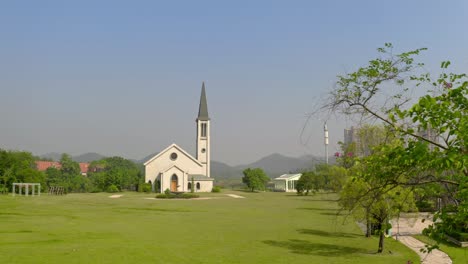 Catholic-style-church-building-without-a-cross-surrounded-with-green-grass-fields-on-a-bright-clear-day