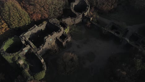 Shaded-derelict-Liverpool-castle-replica-ruins-in-Autumn-Rivington-woodland-nature-landscape-aerial-rising-view