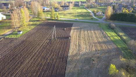 Agricultural-Farm-Tractor-Plowing-Dirt-Field-in-Farming-Community---Aerial