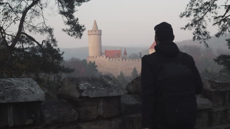 Male-photographer-taking-photo-of-Kokorin-castle-in-background,-Czech-Republic,-middle-shot