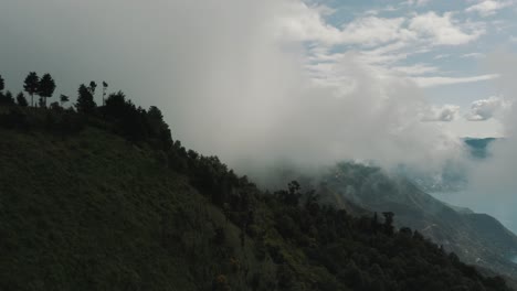 Drohne-Luftaufnahme-Rotiert-Auf-Der-Spitze-Eines-Berges,-Die-Silhouette-Von-Bäumen-Neben-Den-Wolken-Im-Atitlan-see,-Guatemala