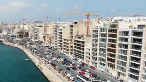 Aerial-4k-drone-footage-flying-towards-a-heavy-trafficked-area-of-a-coastal-city-block-of-Sliema,-a-densely-populated-Mediterranean-community-on-the-island-of-Malta