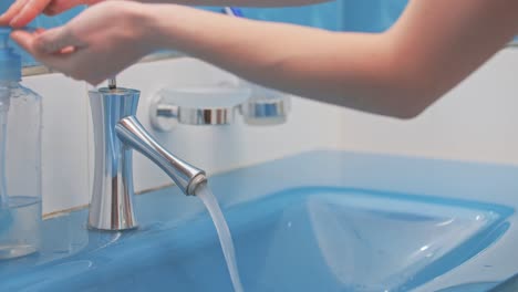 The-girl-washes-her-hands,-using-liquid-soap,-in-a-beautiful-blue-sink