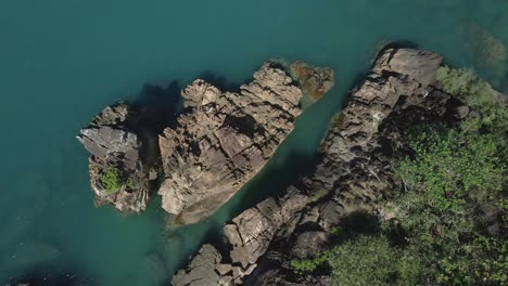 Aerial-down-view-rotating-tropical-ocean-granite-rock-formation-turquoise-water