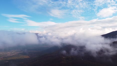 Drone-shot-over-the-low-clouds-flying-above-a-mountain-on-a-sunny-day