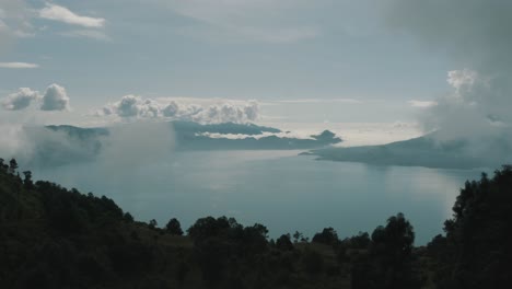 Drone-aerial-view,-flying-over-silhouette-trees,-revealing-beautiful-blue-lake-Atitlan,-Guatemala