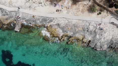 Rocky-sea-shore-eroded-by-the-Mediterranean-turquoise-sea-in-Sliema,-Malta---Rocket-aerial-shot