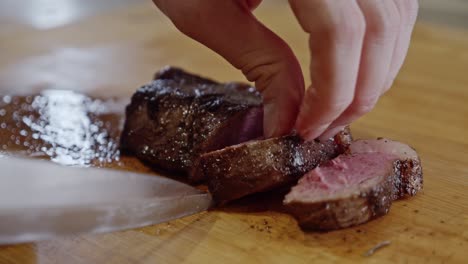 Cutting-fried-steak-into-pieces-on-a-wooden-cut-board-with-a-steel-knife