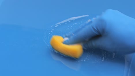 A-woman-in-blue-rubber-gloves-cleans-the-table-with-a-sponge-with-a-foaming-detergent