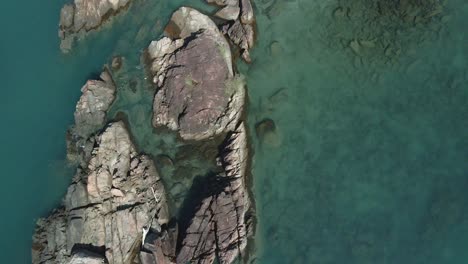 Aerial-backwards-dolly-top-view-granite-rocky-tropical-coastline-turquoise-ocean