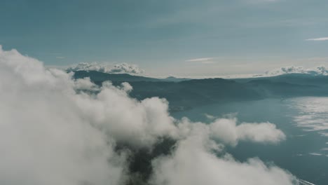 Drone-aerial-flying-next-to-the-clouds-revealing-a-beautiful-landscape-of-Lake-Atitlan-and-surrounding-volcanoes-in-Guatemala