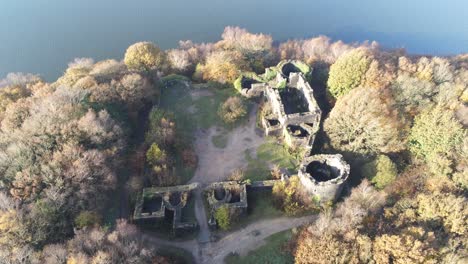 Elevated-Liverpool-castle-replica-ruins-in-Autumn-Rivington-reservoir-woodland-nature-Landmark-aerial-view-tilt-up