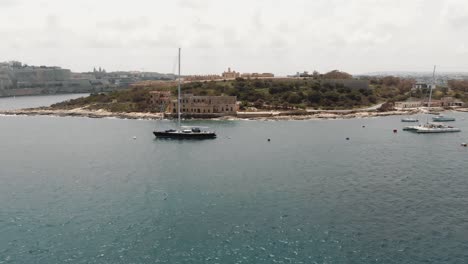 Manoel-Island-Coast-line-from-the-Tigné-Seafront-in-Sliema-city-in-Malta---Ascending-wide-aerial-shot