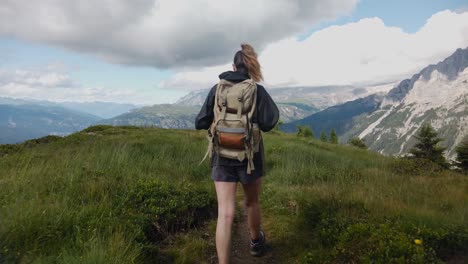 Vista-Desde-Atrás-De-Una-Mujer-Viajera-Turística-Excursionista-Con-Mochila-Haciendo-Senderismo-Y-Caminando-Por-Un-Sendero-De-Montaña-Con-Los-Dolomitas-Al-Fondo