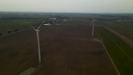 Aerial-shot-of-spinning-propeller-of-wind-turbine-on-agricultural-field-in-the-morning