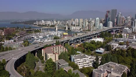 Aerial-Hold-Granville-Island-Bridge,-Die-In-Die-Innenstadt-Von-Vancouver-Führt,-False-Creek,-Der-In-Die-Englische-Bucht-Von-Yaletown-Führt,-Der-Hauptstadtkern-Mit-Einem-Bg-Nebligen-Horizont-Der-Nordwest-Vancouver-Berge-2-2