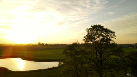 Sonnenlicht-Reflektiert-Und-Leuchtet-An-Einem-Ruhigen-See-Auf-Einer-Wiesenlandschaft-In-Der-Nähe-Des-Dorfes-In-Lubawa,-Polen,-Weitwinkelaufnahme