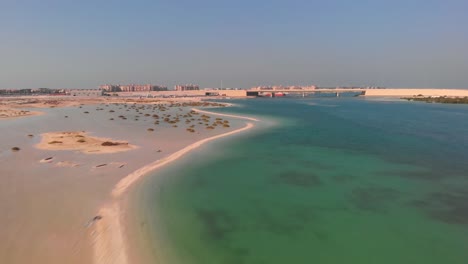 Sandy-coastline-Bridge-and-Middle-Eastern-city-in-the-background,-Drone-Aerial
