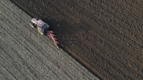 Birds-eye-view-of-tractor-ploughing-dry-fields-ready-for-planting,-Overhead-aerial-View