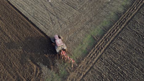 Birds-eye-view-of-a-tractor-starting-to-plough-a-row-in-a-field