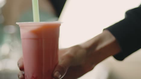 Man's-Hand-Shaking-The-Red-Colored-Bubble-Tea-With-Drinking-Straw