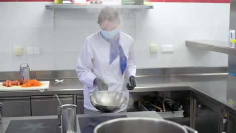 Chef-with-face-mask-is-cooking-a-meal-in-a-hotel-kitchen