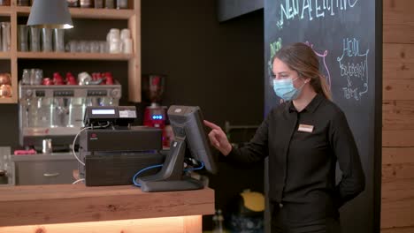 A-waitress-with-face-mask-checks-the-orders-on-a-screen-next-to-the-bar-counter