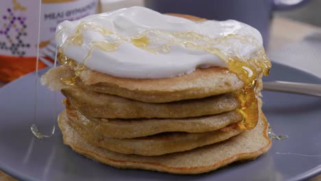 Drizzling-honey-on-a-yummy-stack-of-pancakes-and-yogurt