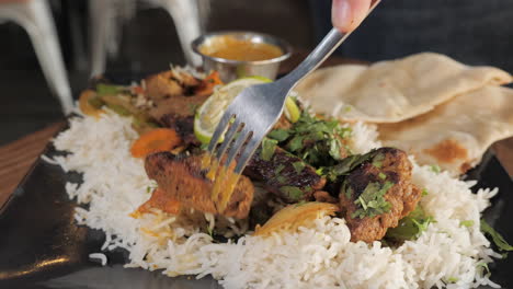 Fork-takes-beef-from-kabob-plate-with-rice-and-naan,-slow-motion-close-up-slider-pull-4K