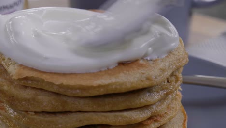 Close-up-of-placing-a-dollop-of-yogurt-on-pancakes