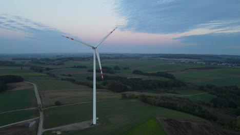 Luftaufnahme-Von-Windkraftanlagen,-Die-Sich-Mit-Schöner-Grüner-Natur-Und-Sonnenuntergangsfarben-Im-Hintergrund-Drehen
