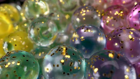 Macro-view-of-glass-spheres-wet-abstract-light-reflections-with-colors-and-golden-glitter,-interesting-4k-bright-fun-background-footage