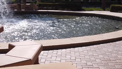 Pan-from-a-brick-walk-surround-across-the-water-retention-basin-of-a-fountain,-Scottsdale,-Arizona
