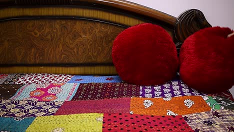 woman-making-over-bed-adjusting-red-velvet-pillow-on-bed