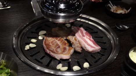 Samgyeopsal---Grilling-Korean-Pork-Belly-Barbeque-With-Garlic-On-Griller-In-A-Restaurant
