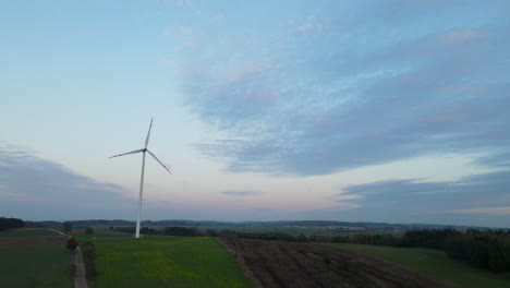 Aerial-drone-shot-of-one-renewable-wind-turbine-during-early-morning-with-sunrise