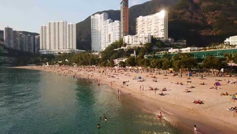 A-moving-aerial-view-of-visitors-at-Repulse-Bay-beach-in-Hong-Kong-as-public-beaches-reopening,-after-months-of-closure-amid-coronavirus-outbreak,-to-the-public